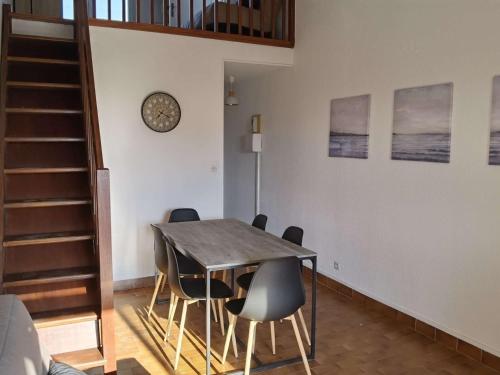 une salle à manger avec une table, des chaises et une horloge dans l'établissement Appartement 2 pièces avec mezzanine et toit terrasse, Marseillan-Plage, 6 couchages - FR-1-326-720, à Marseillan