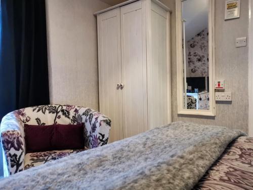 a bedroom with a bed with a chair and a cabinet at Brooklands Guest House in Bowness-on-Windermere