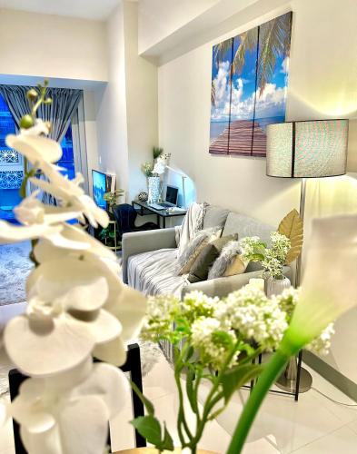 een woonkamer met een bank en een tafel met bloemen bij Lovely 1bedroom in Parksuites in Manilla