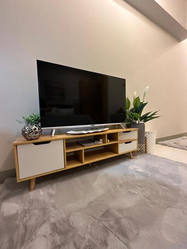 a living room with a television on a wooden entertainment center at BGC, Uptown Parksuites Tower 2 in Manila