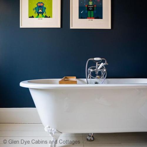 uma banheira branca num quarto azul com duas fotografias em North Lodge & River Cabin em Banchory
