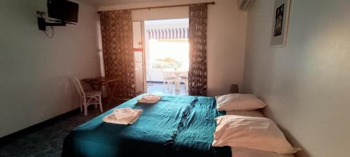 una camera da letto con un letto con lenzuola blu e una finestra di Résidence Madicréoles a Le Carbet