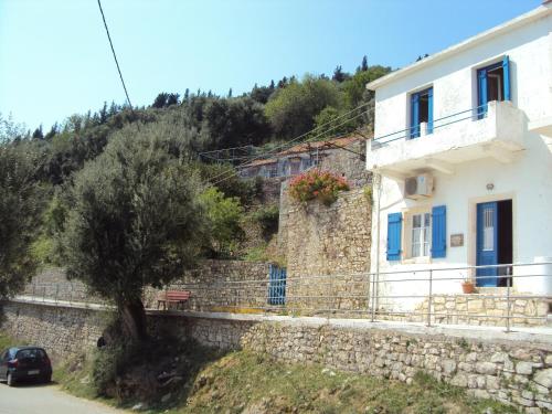 a white house with blue doors on a stone wall at Studio Fetsi in Kiónion