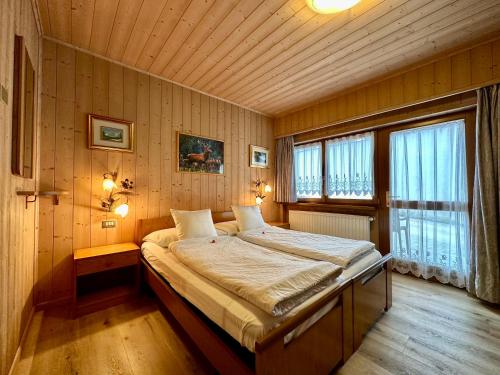 a bedroom with a large bed in a room with wooden walls at B&B Family Accommodation Canazei BIKE FRIENDLY in Canazei