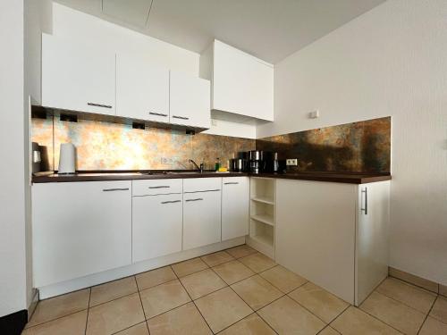 a white kitchen with white cabinets and a tile floor at Aparthotel Altes Dresden in Dresden