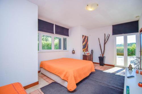 a bedroom with an orange bed and windows at Yuccas House in Sesimbra