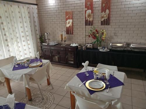 uma sala de jantar com duas mesas e um buffet em THATCH HAVEN GUEST HOUSE em Mahikeng