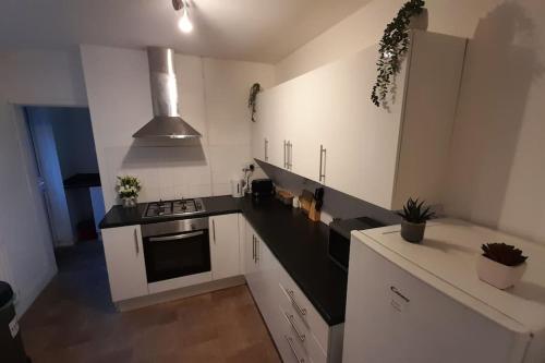 a kitchen with white cabinets and a black counter top at Spacious 4 Bedroom, Free Netflix, Central Location in Cardiff