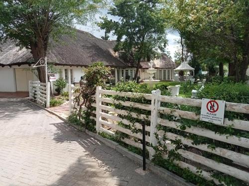 a white fence with a no bikes sign in front of a house at Thatch Haven Guesthouse in Mahikeng