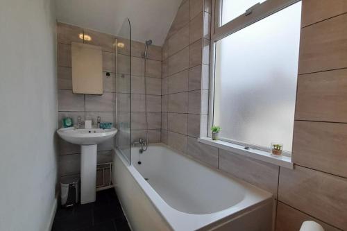 een badkamer met een wastafel, een bad en een wastafel bij Spacious 4 Bedroom, Free Netflix, Central Location in Cardiff
