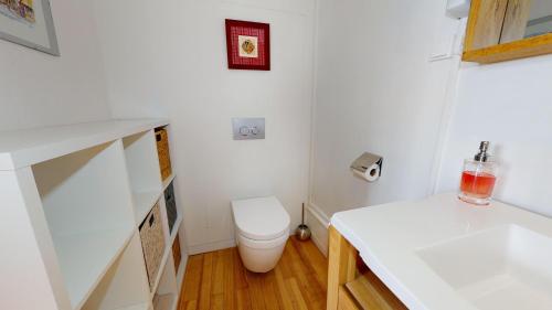 La salle de bains blanche est pourvue de toilettes et d'un lavabo. dans l'établissement Le Clos bartholdi, à Colmar