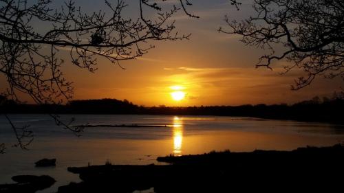 a sunset on a lake with the sun setting at River View in Aldeburgh