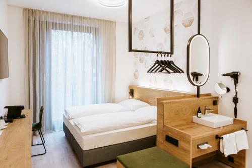 a bedroom with a bed and a mirror and a sink at BEE GREEN Linz Self-Check-in-Hotel in Linz