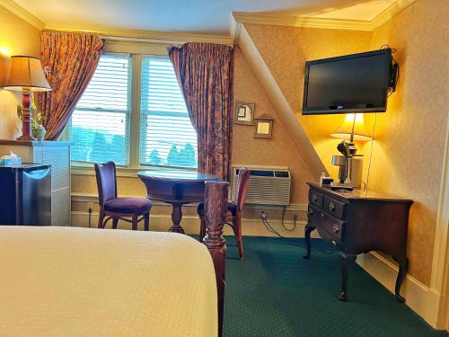 um quarto de hotel com uma cama, uma mesa e uma televisão em Winthrop Arms Hotel Restaurant Logan Airport em Winthrop