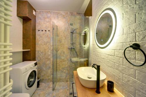 uma casa de banho com um lavatório e uma máquina de lavar roupa em Trevilles Apartamenty Pogodny em Szklarska Poręba