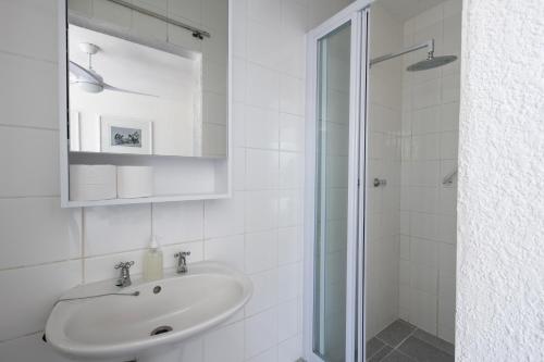 a white bathroom with a sink and a shower at Cape Agulhas Guest House in Agulhas