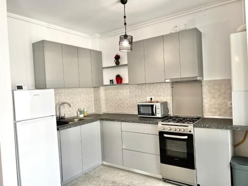 een witte keuken met witte kasten en een magnetron bij Apartment Mara 2 in Timişoara