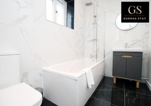 uma casa de banho branca com uma banheira e um WC em 4 Bedroom Modern House, Perfect for Int-Students, Family Relocations, Groups & Contractors by Gurkha Stay Cardiff With Off-Road Parking & WiFi em Cardiff