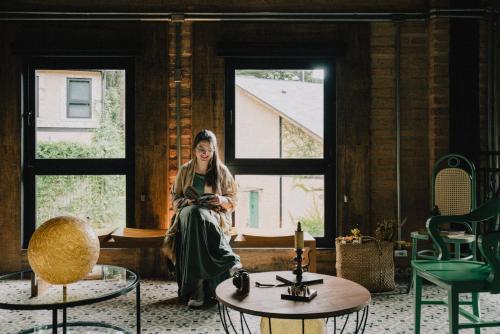 a woman sitting on a window sill in a room at LA PIANTA - Uma experiência na Villa de Monte Verde in Monte Verde