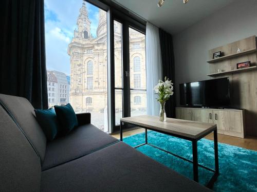 a living room with a couch and a table and a large window at Panoramastudio mit Blick zur Frauenkirche in Dresden