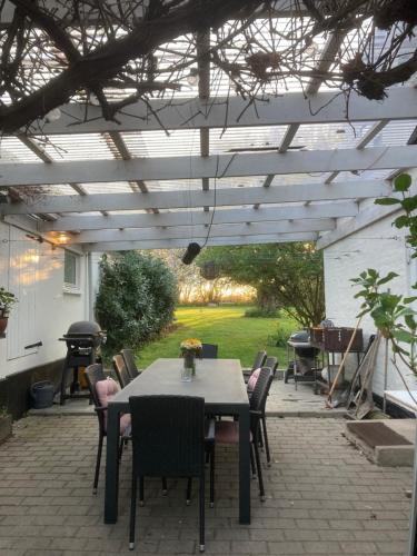 a patio with a table and chairs under a pergola at Vejskrækgården in Fæbæk