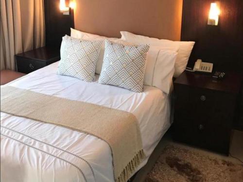 a large bed with white sheets and pillows at Le Chef BnB in Mthatha