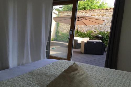 ein Schlafzimmer mit einem Bett und eine Terrasse mit einem Sonnenschirm in der Unterkunft Bergerie Truphemus de Savoillan in Savoillan