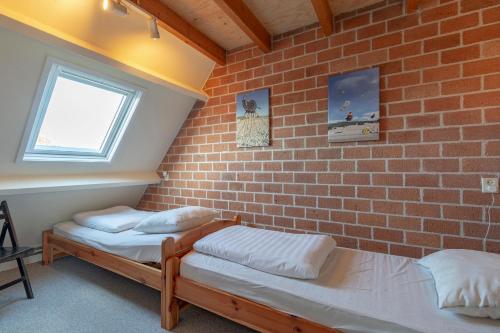 um quarto com duas camas contra uma parede de tijolos em Abbestederweg 24A Callantsoog em Callantsoog