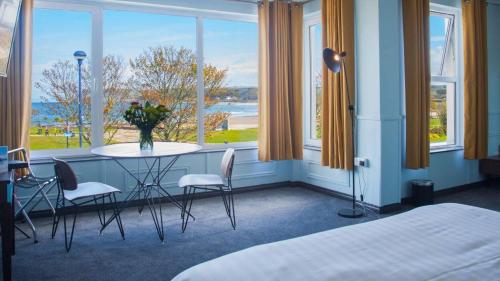 a room with a table and chairs and windows at Marine Hotel Ballycastle in Ballycastle