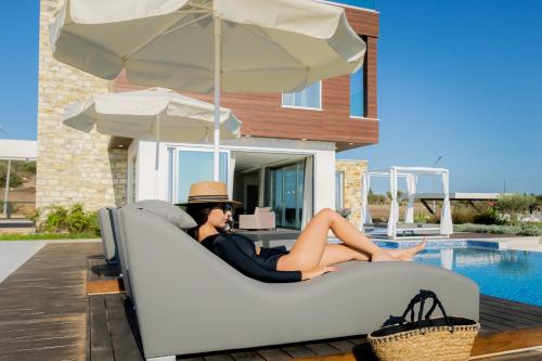 a woman sitting on a couch next to a pool at Love Bridge Seaview Villas in Ayia Napa