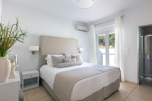 a white bedroom with a large bed and a window at Villa Panorama in Chania Town