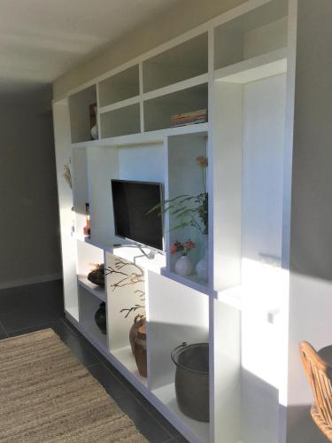 a white book shelf with a tv in it at House of Flowers, Gendringen, Achterhoek, Gelderland in Gendringen