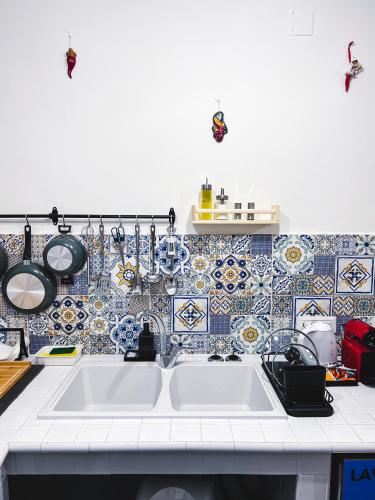- une cuisine avec un évier et du carrelage bleu et blanc dans l'établissement Terno su Napoli Apartments, à Naples