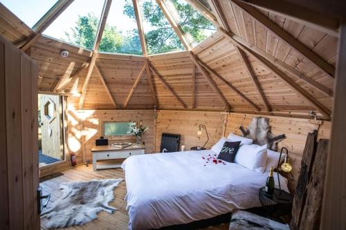 a bedroom with a large bed in a wooden room at Romantic Treehouse with Hot Tub & BBQ Lodge in Praze an Beeble