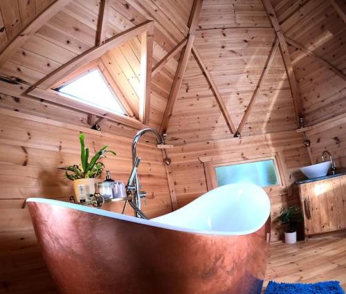 Praze an BeebleにあるRomantic Treehouse with Hot Tub & BBQ Lodgeの木製の部屋のバスルーム(バスタブ付)