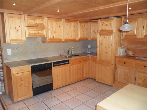 una cocina con armarios de madera y fregadero en Ferienwohnung Haus Bord, en Sankt Antönien