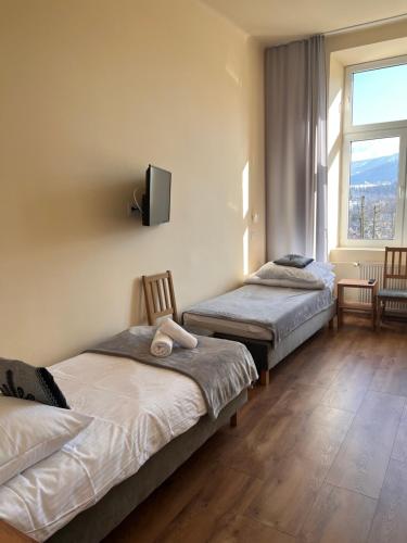 a bedroom with two beds and a tv on the wall at Nauczycielskie Centrum in Zakopane