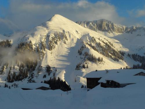 a snow covered mountain with a building in front of it at Ferienwohnung Haus Bord in Sankt Antönien