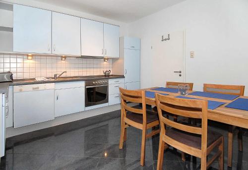 a kitchen with white cabinets and a wooden table with chairs at Ferienhaus Nordseezauber in Esens