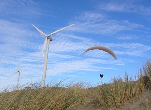 a paraglider flying over two wind turbines at ´t Wapen van Marion in Oostvoorne