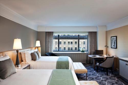 um quarto de hotel com duas camas e uma secretária e uma janela em Loews Regency New York Hotel em Nova Iorque