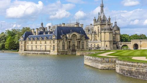 un gran castillo con un lago frente a él en La Vannerie en Béthisy-Saint-Martin