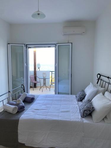 a bedroom with a large white bed with a balcony at Amaltheia Beach Front Houses in Kipseli