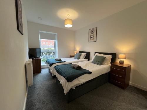 a bedroom with two beds and a television in it at 2 Double beds OR 4 Singles, 2 Bathrooms, FREE PARKING, Smart TV's, Close to Gunwharf Quays, Beach & Historic Dockyard in Portsmouth