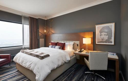 a hotel room with a bed and a desk and a window at The Lofton Hotel Minneapolis, Tapestry Collection by Hilton in Minneapolis