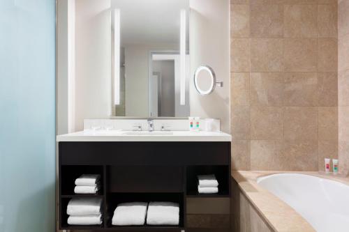 a bathroom with a sink and a tub and a mirror at The Lofton Hotel Minneapolis, Tapestry Collection by Hilton in Minneapolis