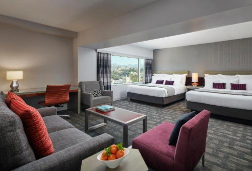 Habitación de hotel con 2 camas y sofá en Loews Hollywood Hotel en Los Ángeles