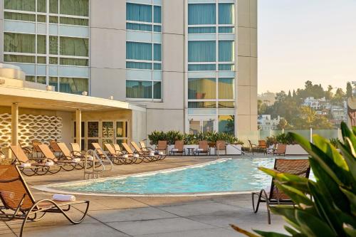 un hotel con piscina con sillas y un edificio en Loews Hollywood Hotel, en Los Ángeles