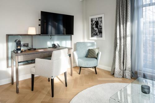 Zimmer mit einem Schreibtisch, einem Stuhl und einem TV in der Unterkunft Clounys Hotel in Hamburg