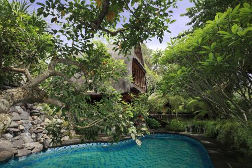 a swimming pool in front of a house with trees at Omah Pakem in Pakem